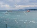 A pilot boat leads a container vessel to port. Luka Koper (`Capo