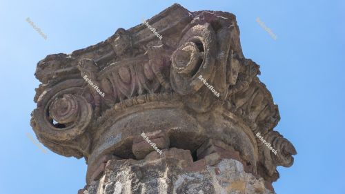 Ancient Roman column capital (head) with blue sky in the backgro Ancient Roman column capital (head) with blue sky in the backgro