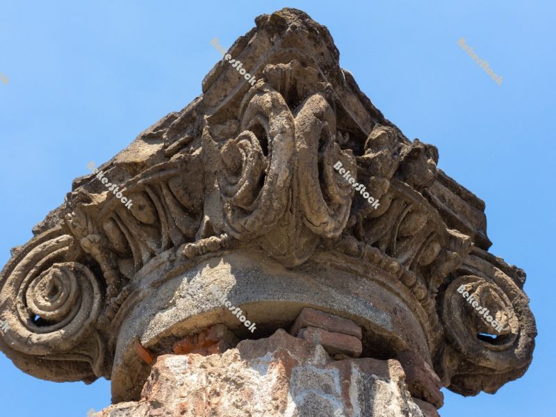 Ancient Roman column capital (head) with blue sky in the backgro Ancient Roman column capital (head) with blue sky in the backgro