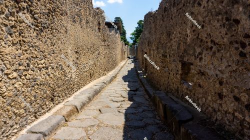 Street (`via`) in Pompeii. The narrow street is lined with stone Street (`via`) in Pompeii. The narrow street is lined with stone
