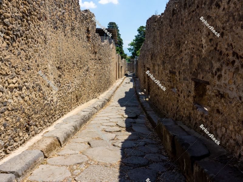 Street (`via`) in Pompeii. The narrow street is lined with stone Street (`via`) in Pompeii. The narrow street is lined with stone